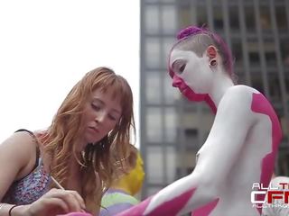 Group of naked people get painted in front of publ